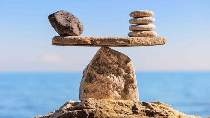 Stones stacked on a boulder represent a balanced scale.