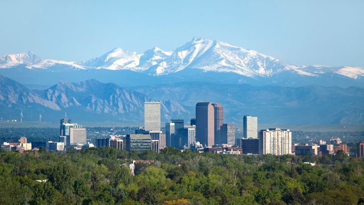 Longs Peak and the surrounding Rocky Mountains loom over the Denver skyline.
