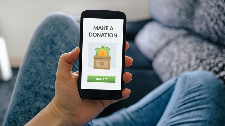 A woman makes a donation on her phone.