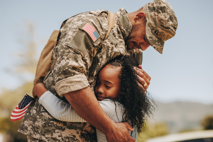 A soldier hugging his daughter before returning to his unit.