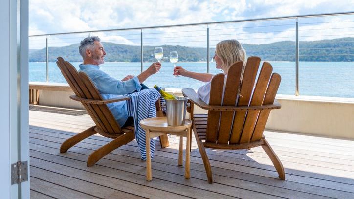 A wealthy couple enjoys a glass of wine together while sailing on a cruise.