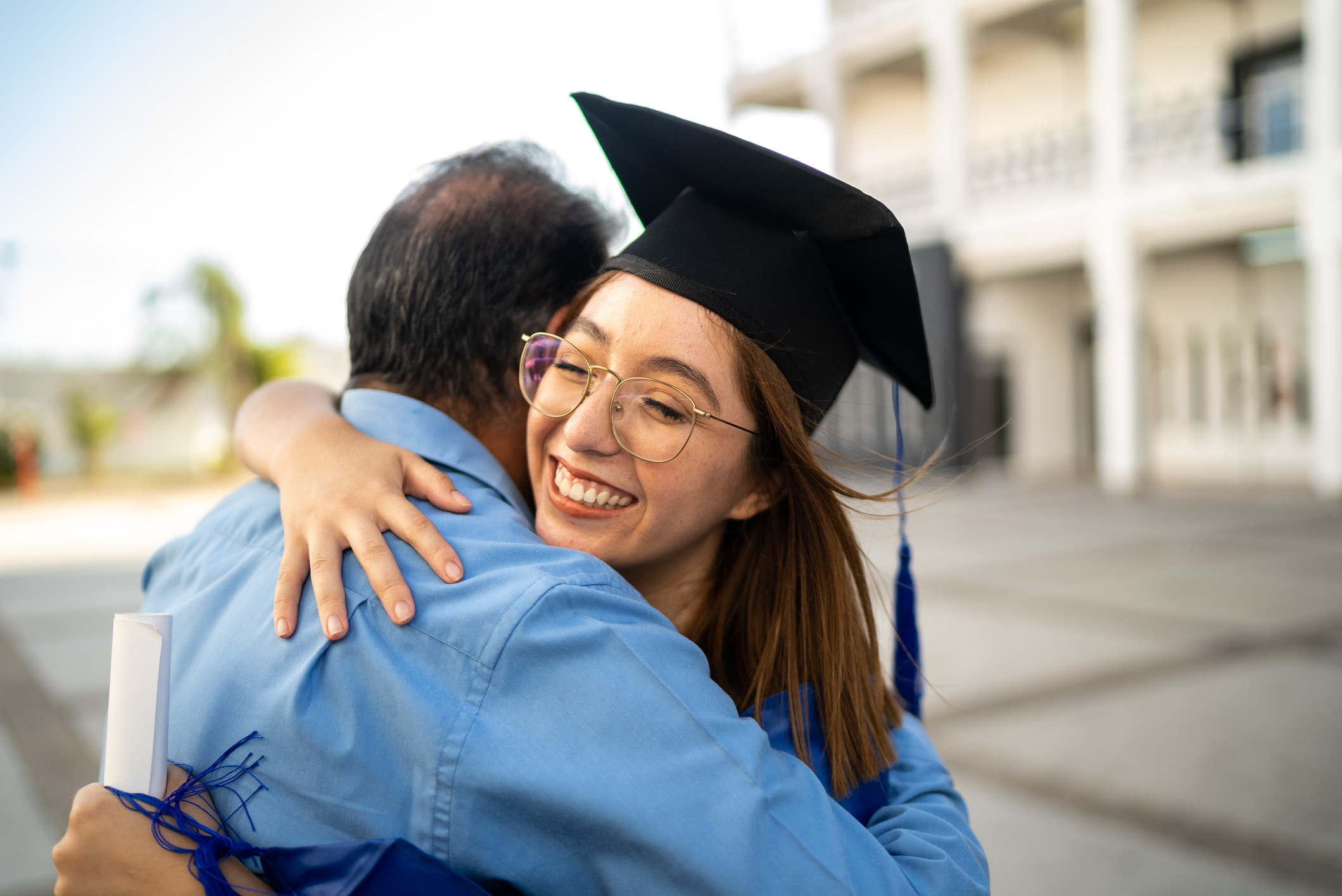 A college graduate hugging her father after receiving her diploma.