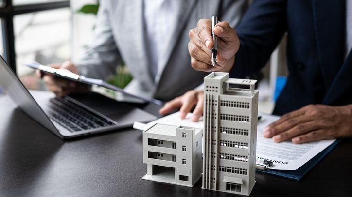 Commercial real estate investors look at a model of an office building they may acquire.