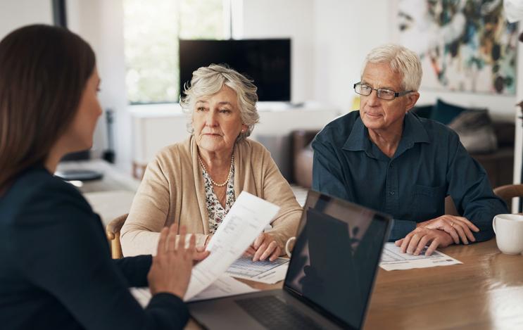 A senior couple meets with a financial advisor to discuss an estate plan for Illinois.