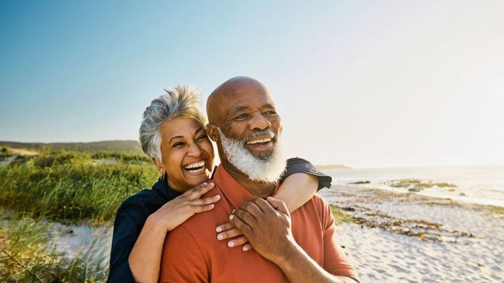 A couple smiles while walking on the beach after deciding that they're financially ready to retire.