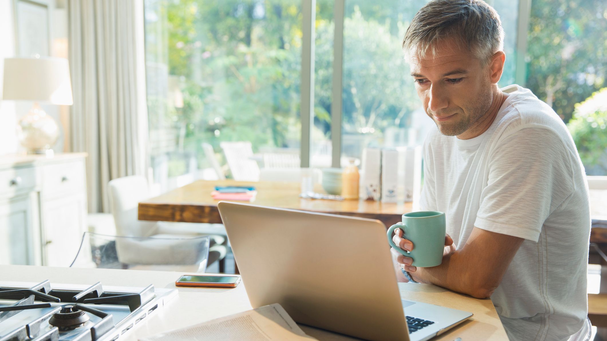 A semi-retired worker checks his email and enjoys a cup of coffee.