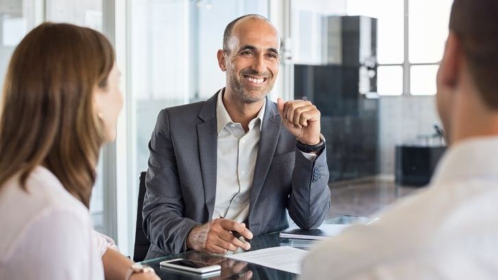 An exempt reporting advisor talks with colleagues during a meeting.