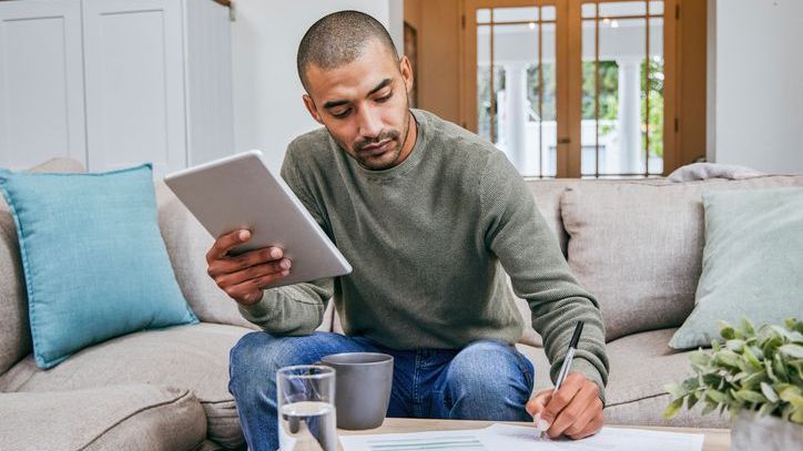 A man checks his investment portfolio and calculates how much it could be worth in 20 years.