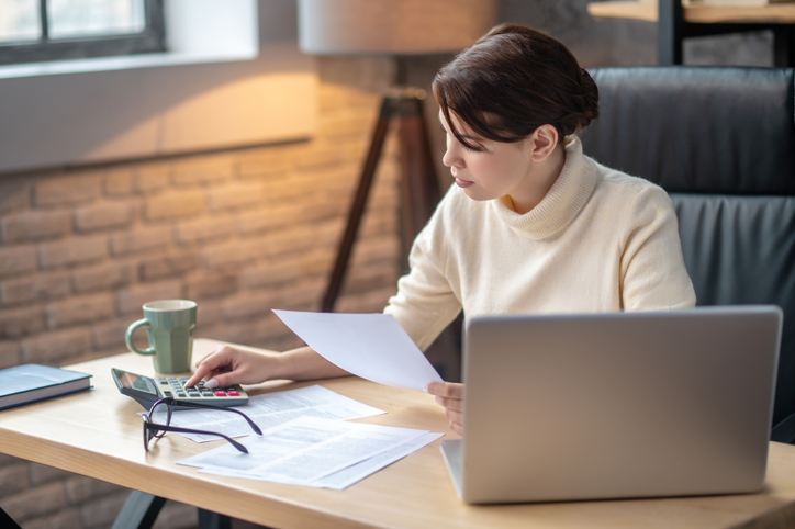 A woman calculating her college expenses. 