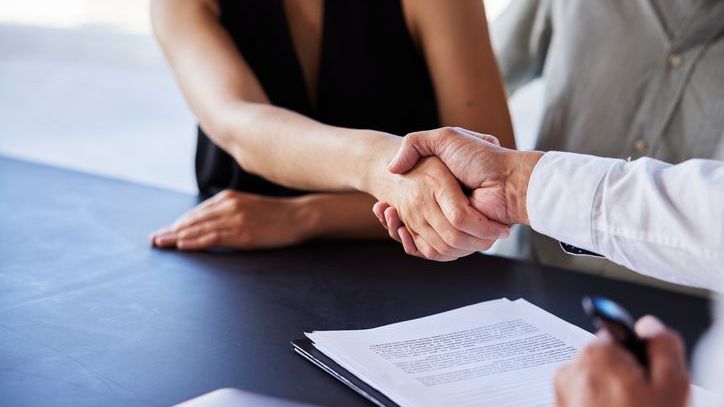 A couple shakes hands with a loan officer after signing their mortgage documents to purchase a home.