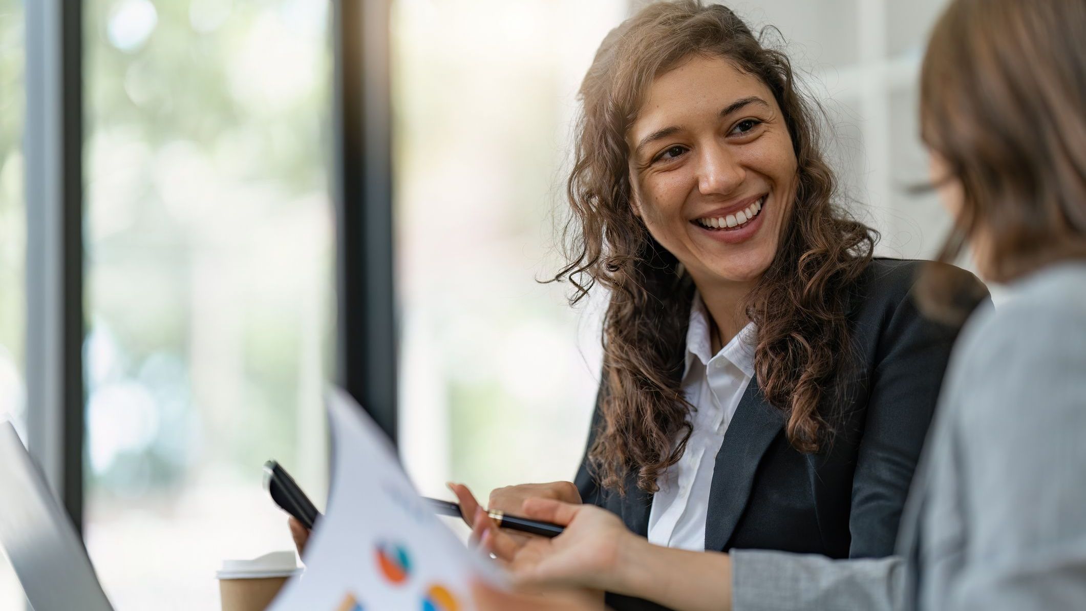 A company's financial manager smiles during a meeting with a colleague.