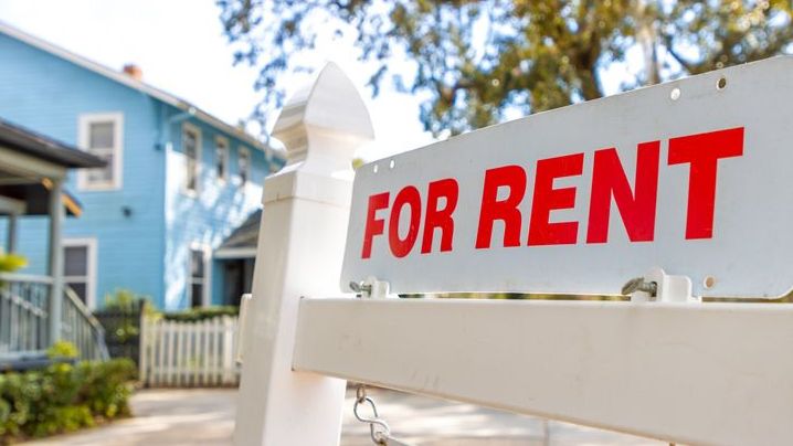 A for rent sign hangs outside of a vacant rental property that's owned by a real estate investor.