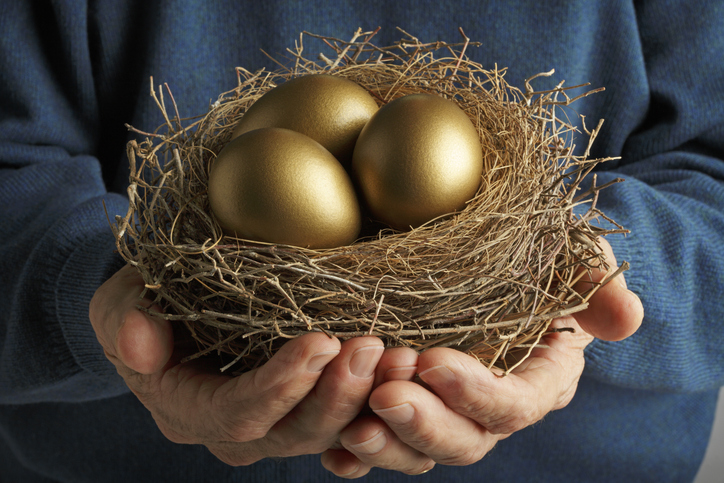 A senior holding three golden eggs in a bird's nest as a symbol of their retirement savings.