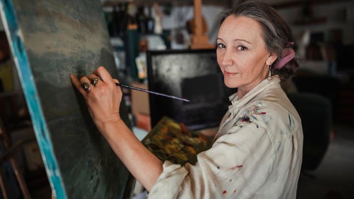 An artist works on a painting in her studio.