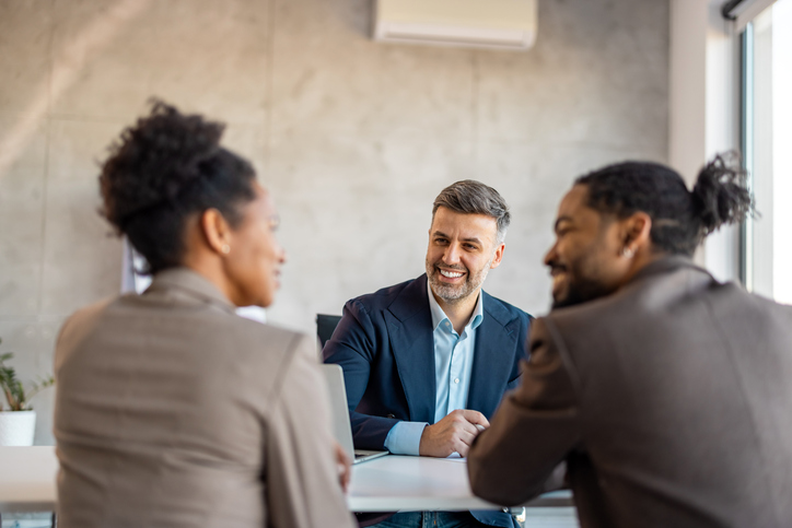 A couple meeting with a financial advisor to review a real estate investment plan.