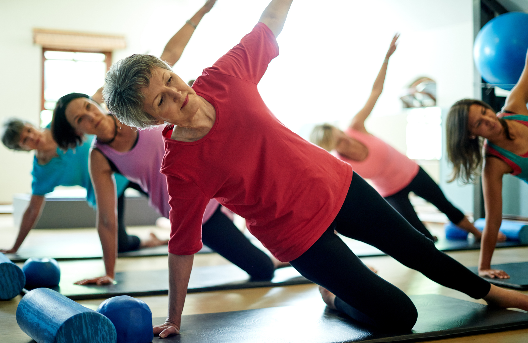 A senior participates in a pilates class that she takes regularly in retirement.