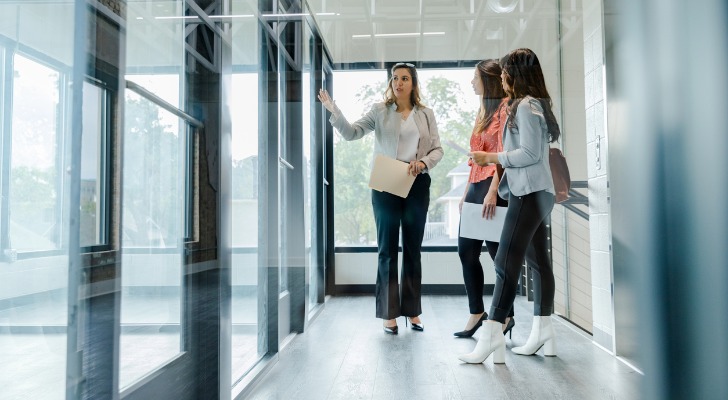 A commercial real estate agent gives a tour of office space to a pair of business partners. 