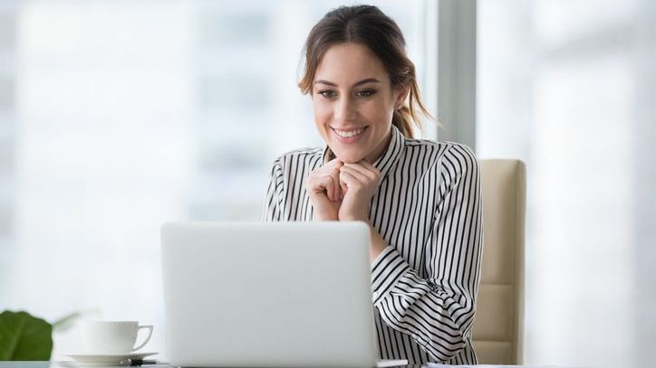 A new investor smiles after opening her first brokerage account on her computer.