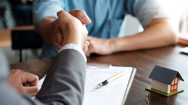 A real estate wholesaler shakes hands with an investor after assigning a contract to them.