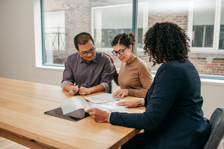 A couple reviewing their real estate portfolio with a financial advisor.