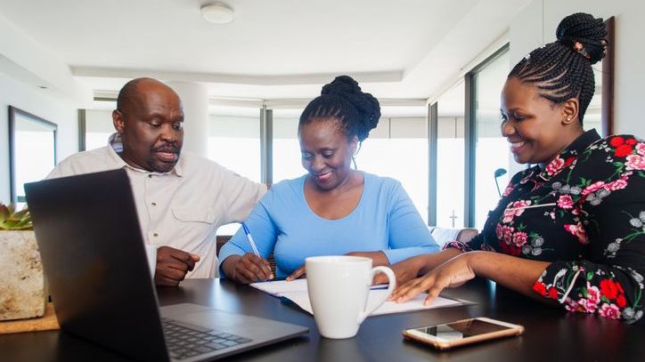 A woman signs her will in front of two family members serving as a witnesses. 