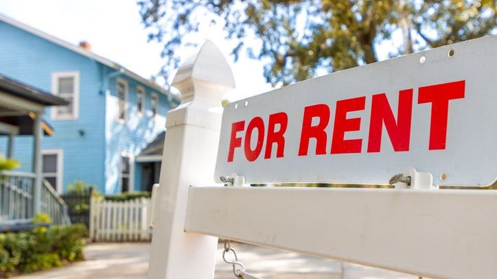 A for rent sign hangs outside of a rental property owned by an income-focused investor.