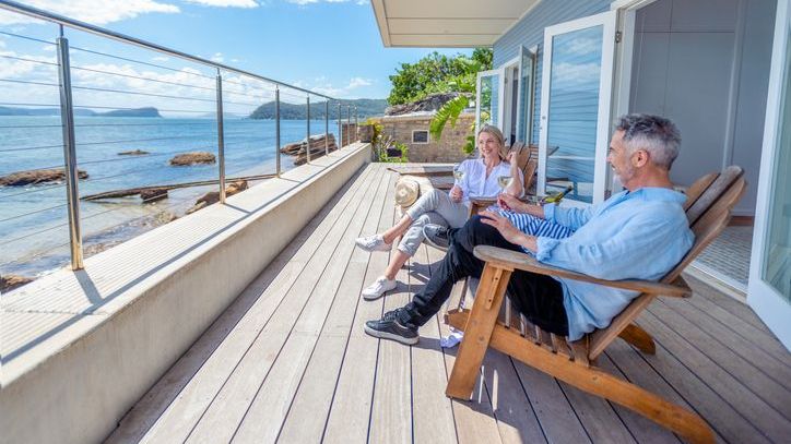 A couple enjoys a glass of wine on the deck of their newly purchased vacation home.