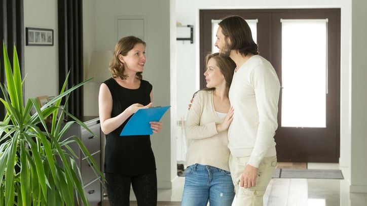 A property owner gives a tour of one of her properties to a couple. 