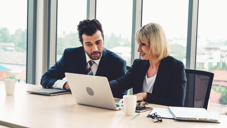 Nasdaq Two financial advisors reviewing investment portfolios for clients.