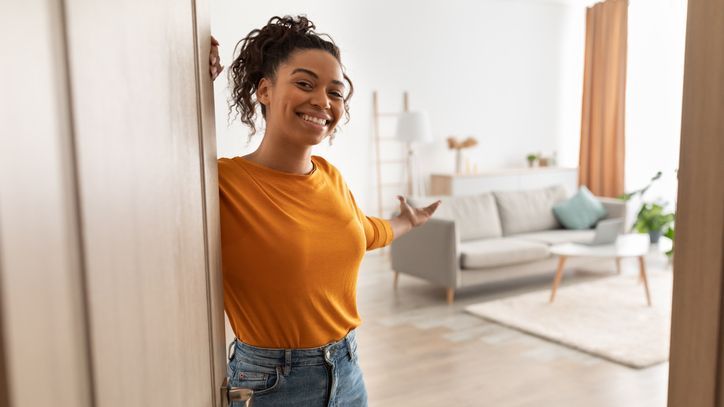 A young real estate investor opens the front door to a rental property she recently purchased.