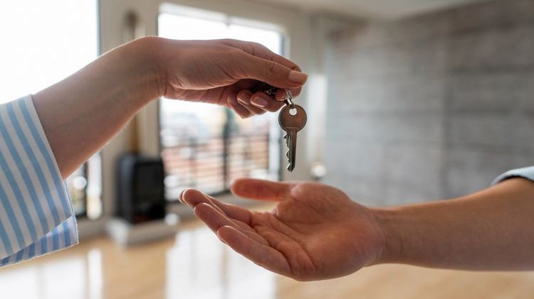 A real estate investor hands the keys to a rental property to a new tenant. 