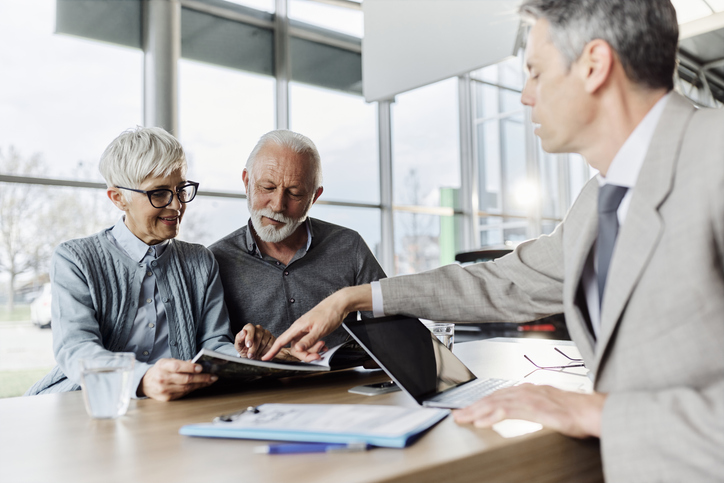 A senior couple creating a retirement budget with a financial advisor.