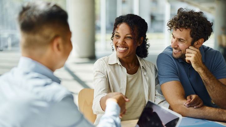 A financial advisor shakes hands with a couple who was referred to him and are now clients.