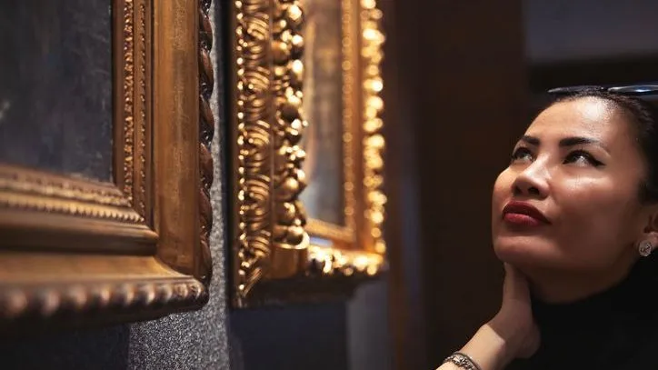 A woman looks at artwork that's for sale. 