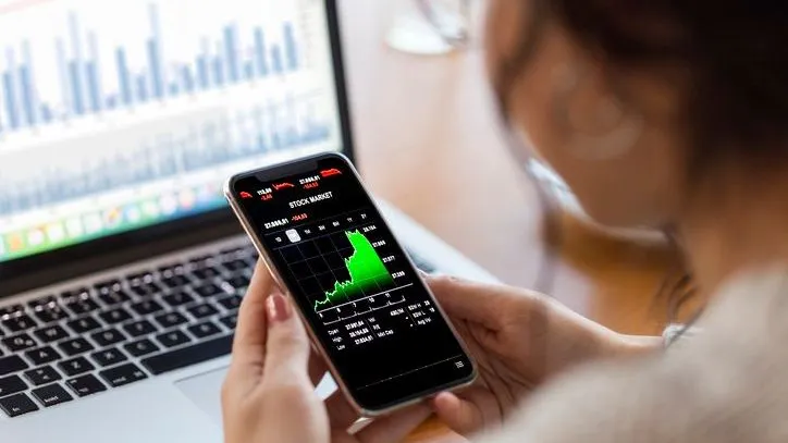 An investor tracks the stock market performance on her smartphone. 