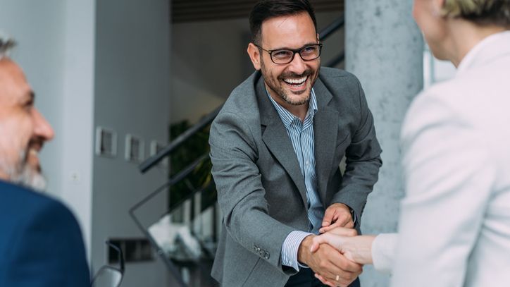 An angel investor shakes hands with the owners of a business that he's investing in.