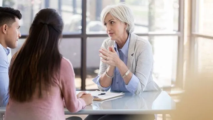 A woman speaks with a couple during a consultation. 