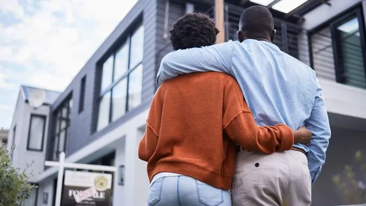 A couple stands in front of their new home.