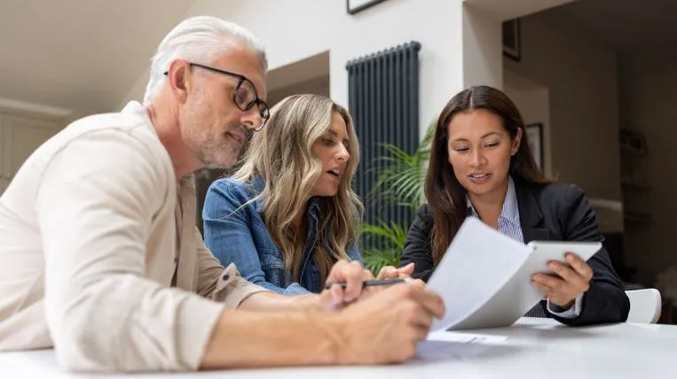 Three people review paperwork together. 