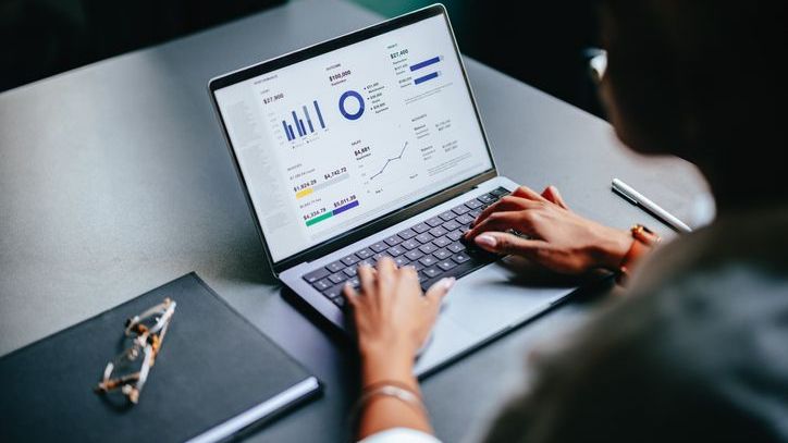 A woman looks at tables and graphs on her laptop.