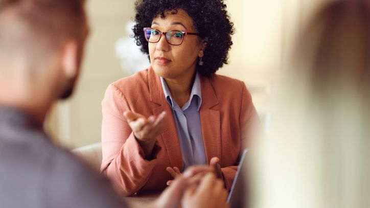 A woman has a conversation with a man in a business setting. 