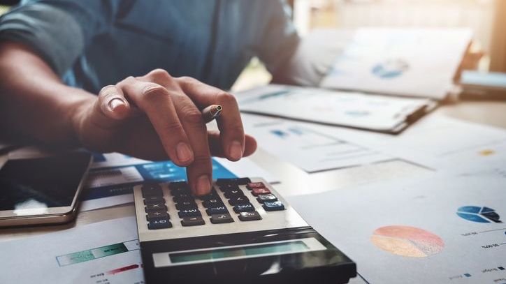 A man plugs numbers into a calculator while looking over data.