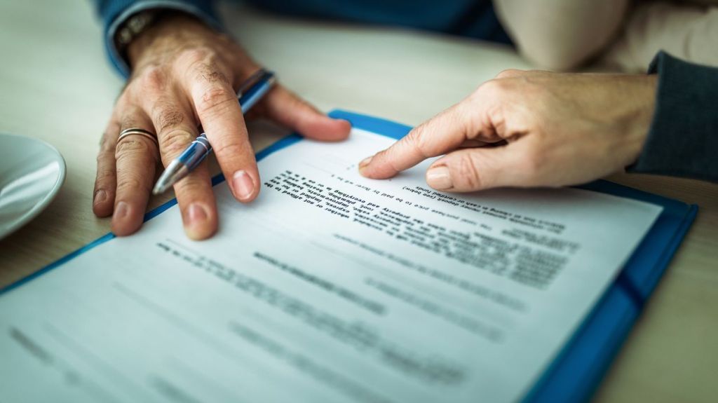 A close up of a person signing a mortgage contract in an office.