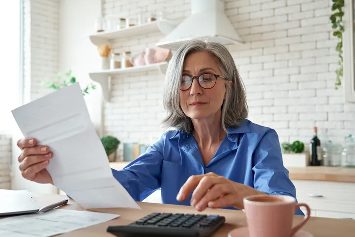 Senior business woman holding a paper statement for her retirement account while calculating her RMD.