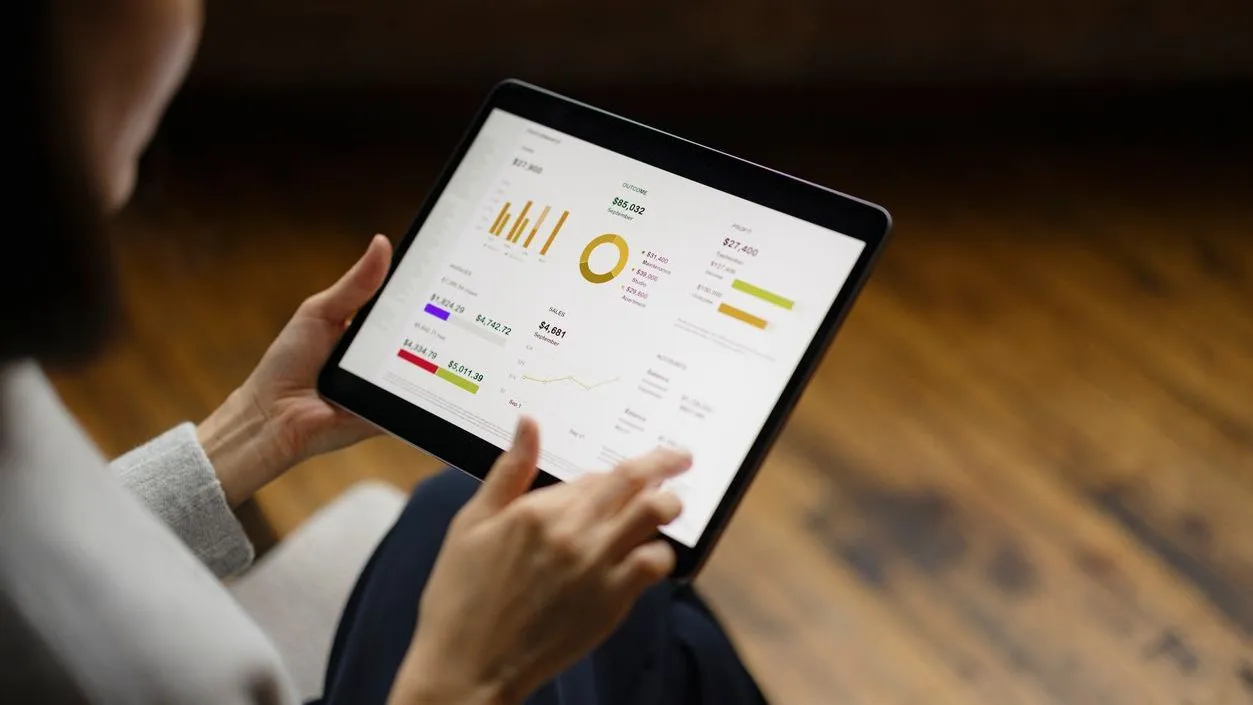 A woman analyzes digital graphs and charts on a tablet. 