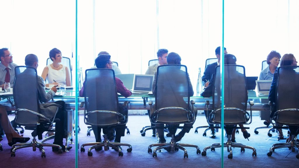 Members of a corporate board meet in a conference room. 