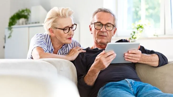 A man and woman review some paperwork on a tablet. 