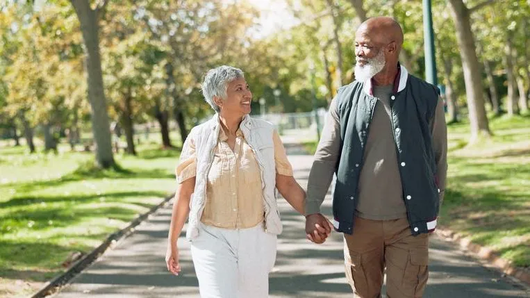 A couple holding hands while on a walk in the park. 