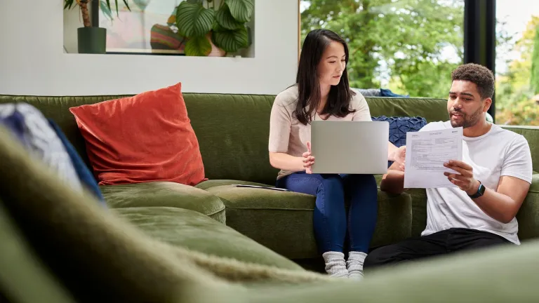 A couple reviews tax documents from their living room couch.