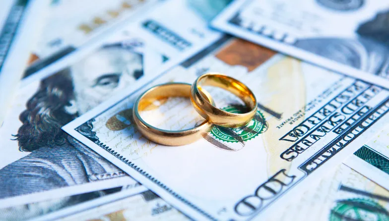 Wedding rings on a spread of cash.